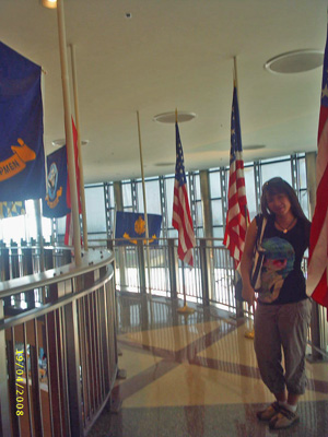 Ann stands in the museum surrounded by flagpoles with the American flag.